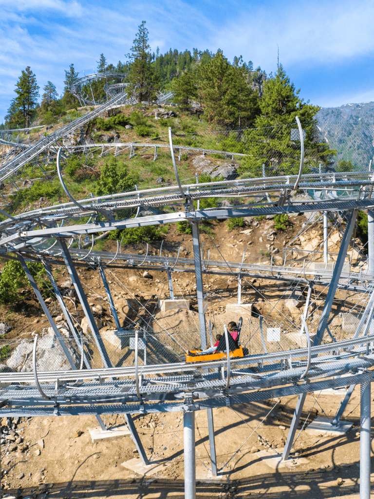 Thrilling roller coaster ride at Quest For Directions amusement park in scenic mountain setting.