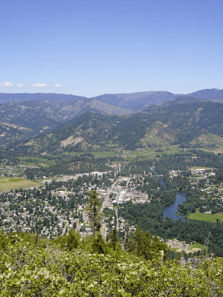 Vast mountain town scenery with lush greenery and river view, inspiring outdoor adventure in Oregon.