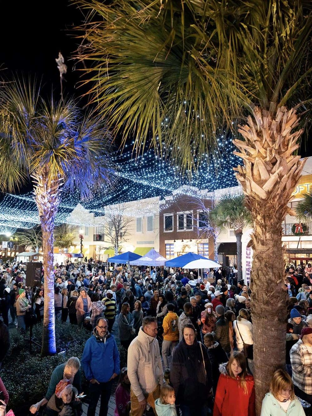 Bright urban night scene with festive holiday lights and large crowd ofpeople enjoying Christmas market.