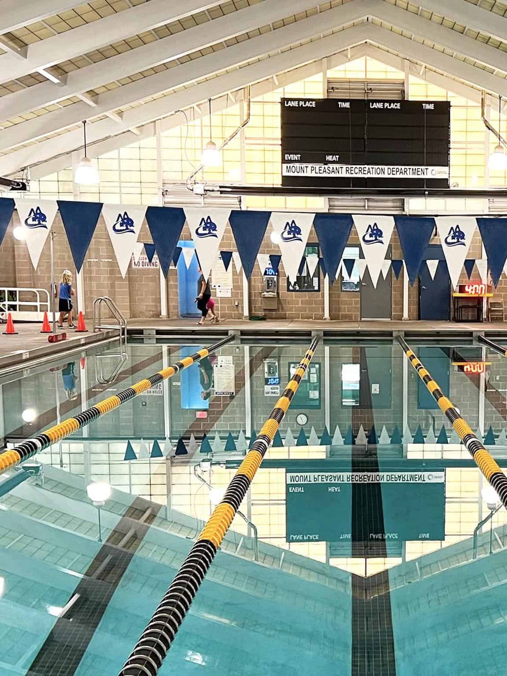 Indoor swimming pool at Mount Pleasant Recreation Department with lanes, spectators, and event signage.