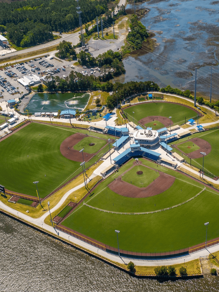 Aerial view of Quest for Directions sports complex with baseball fields, water park, parking, and surrounding greenery.