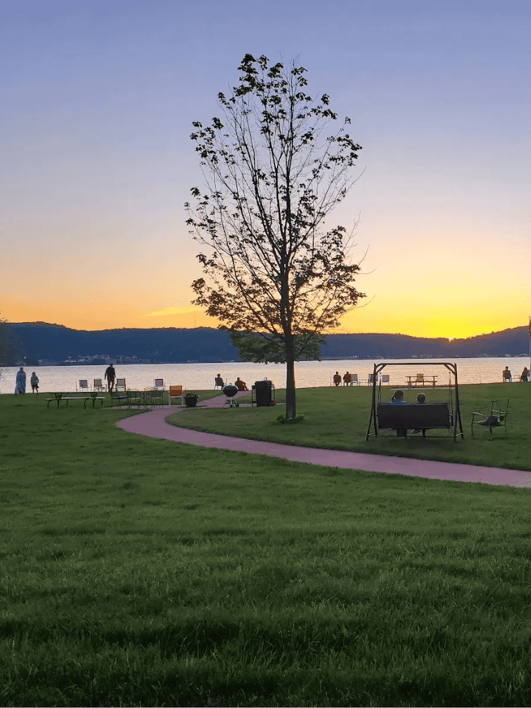 1. Lakefront park during sunset with walking paths, benches, and a swing.