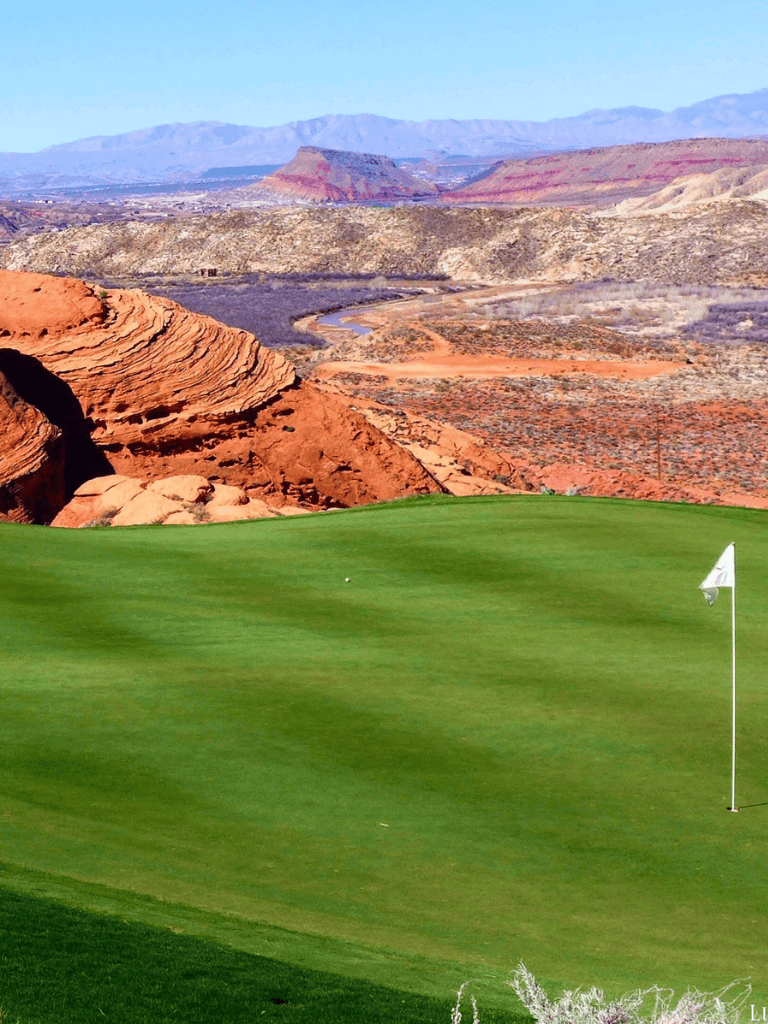 Vibrant desert landscape with a lush golf course in foreground and rugged mountains in background.