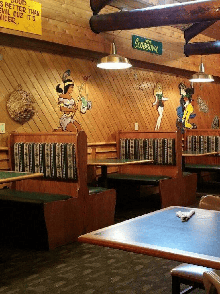 Colorful restaurant booth with cartoon murals and wooden decor, cozy dining ambiance.