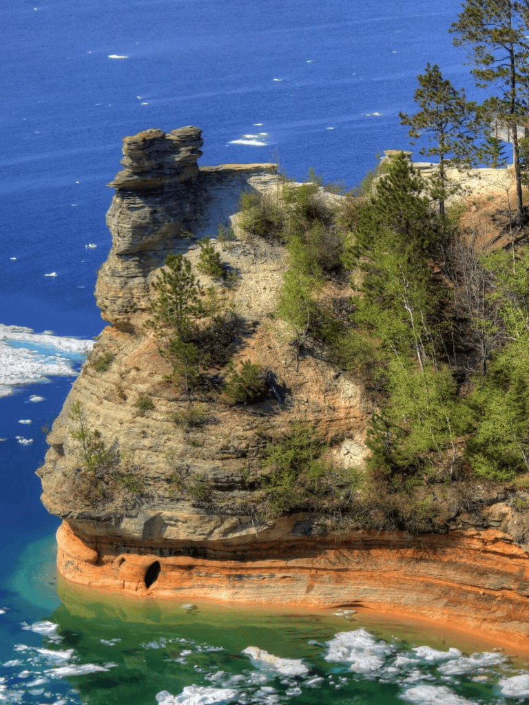 Majestic coastal cliff with unique rock formations and lush greenery overlooking the ocean.
