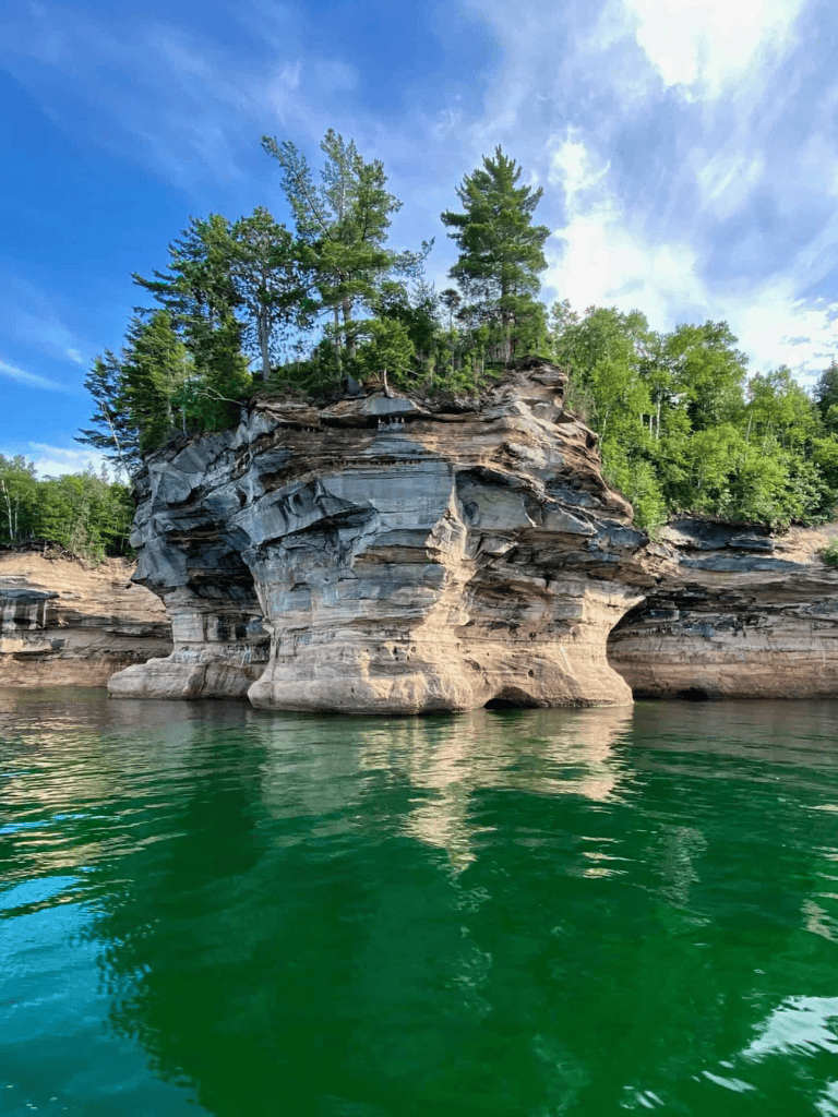 Vast rock formation along Green Lake with lush trees and blue sky, popular for outdoor exploration and scenic views.
