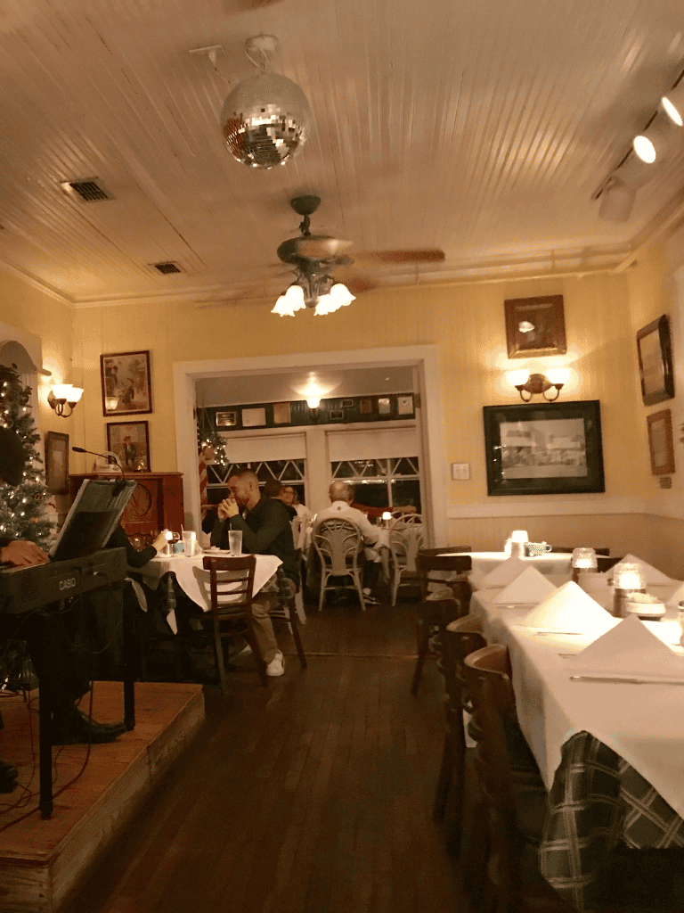 Cozy restaurant interior with white table linens, dim lighting, and festive holiday decorations, ideal for dining out and special occasions.