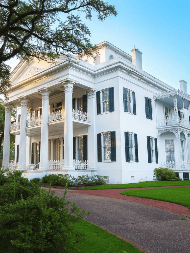 Elegant white mansion with classic architecture and lush green surroundings.