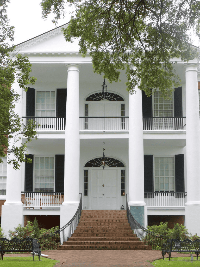 Elegant white southern mansion with grand staircase and columns, perfect for historic home tours.