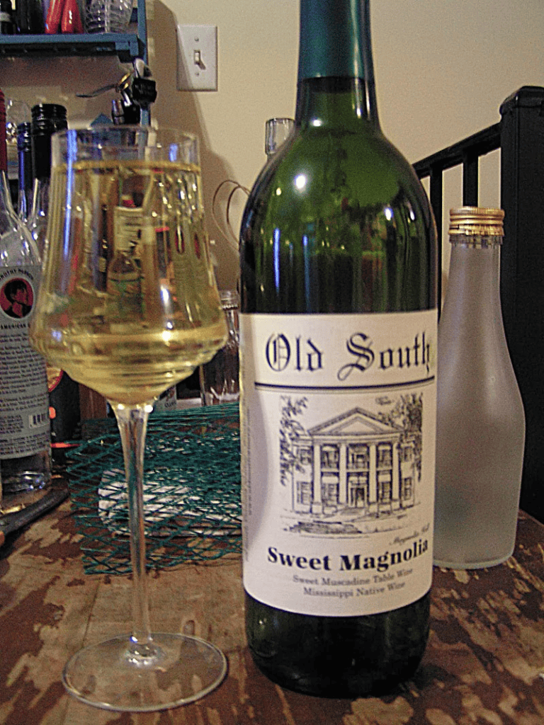 Old South Sweet Magnolias wine, Chardonnay from Mississippi, on a rustic table with glass of wine.