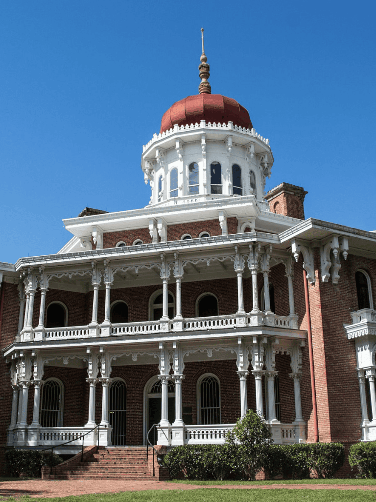 Elegant historic Victorian mansion with ornate white woodwork and red brick façade.