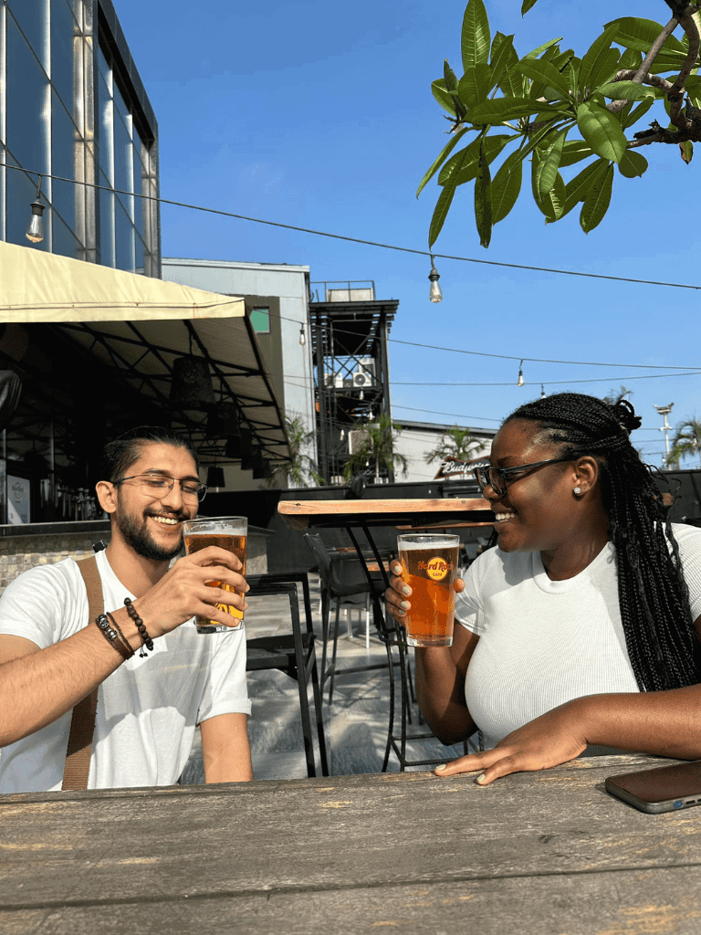 Refreshing outdoor bar scene with two friends enjoying beers and good times on a sunny day.