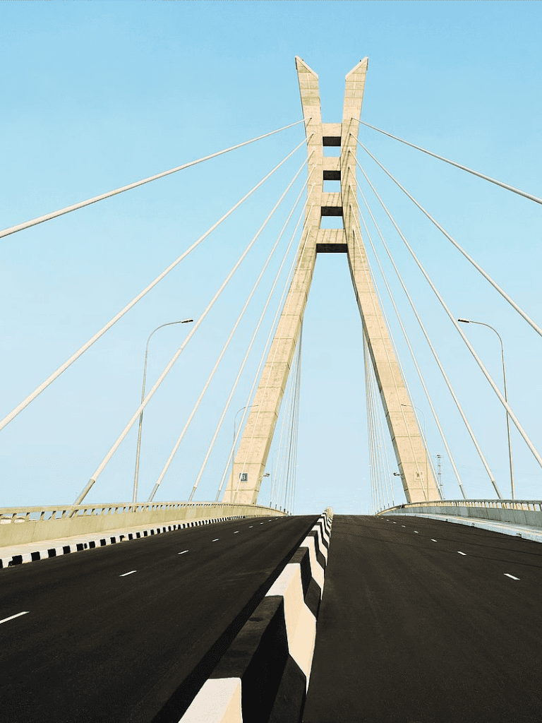 Modern cable-stayed bridge with tall towers and suspension cables over a clear blue sky.