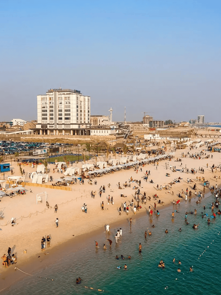 Beach destination with modern hotel, crowded shoreline and clear blue water, in a vibrant coastal city.