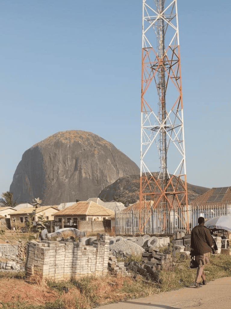Cell tower near Mount Kilimanjaro in Tanzania, with local buildings in the foreground.