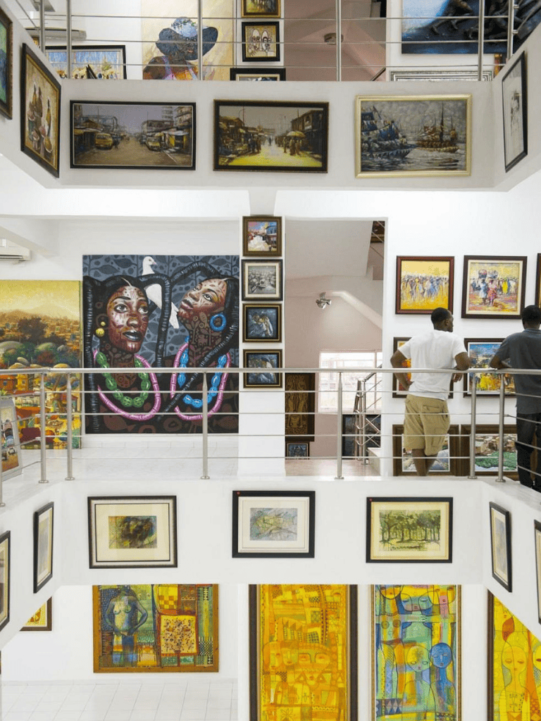 Vibrant art gallery showcasing diverse paintings and murals in a multi-level space.