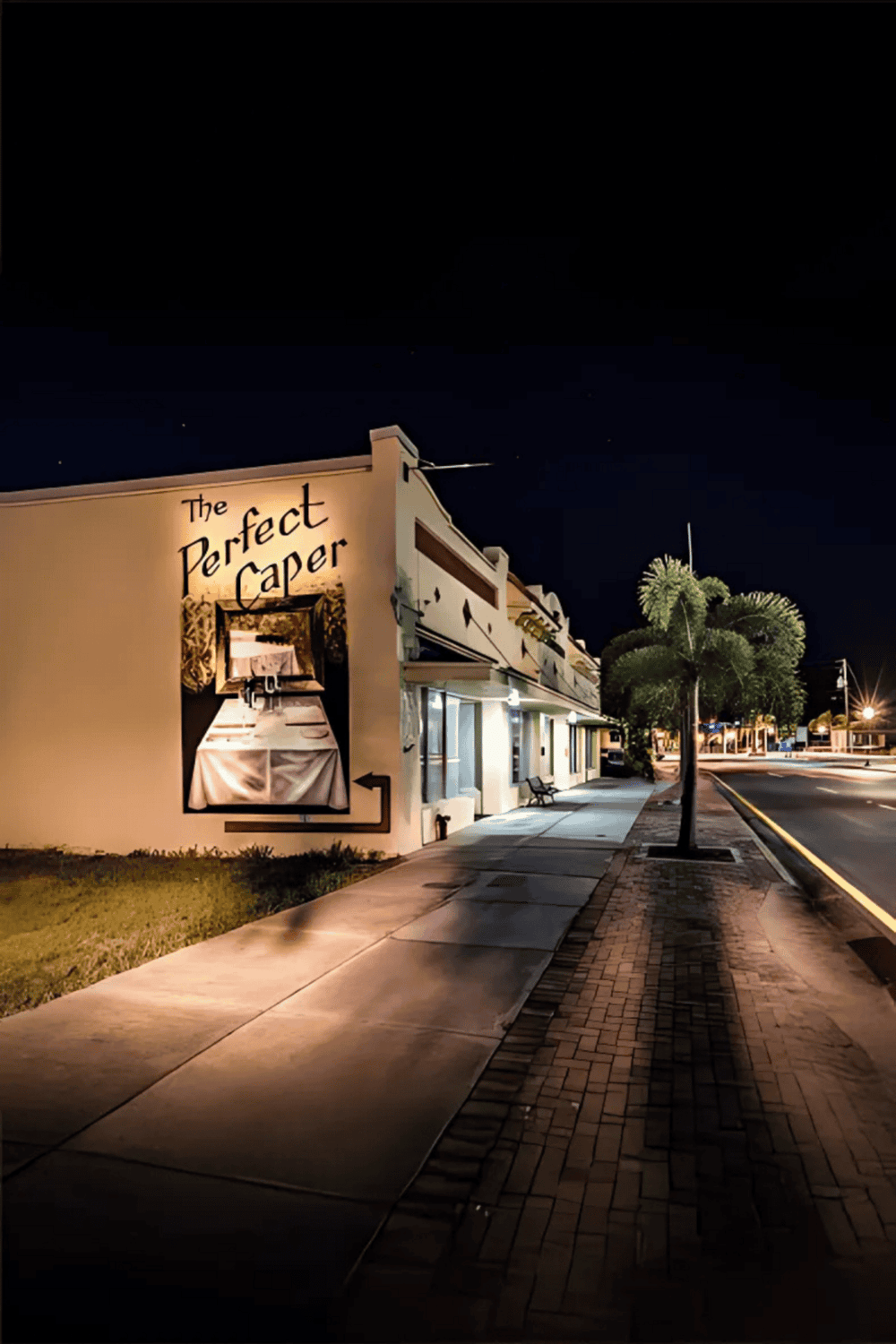 1. Night view of The Perfect Caper restaurant with illuminated signage and sidewalk.