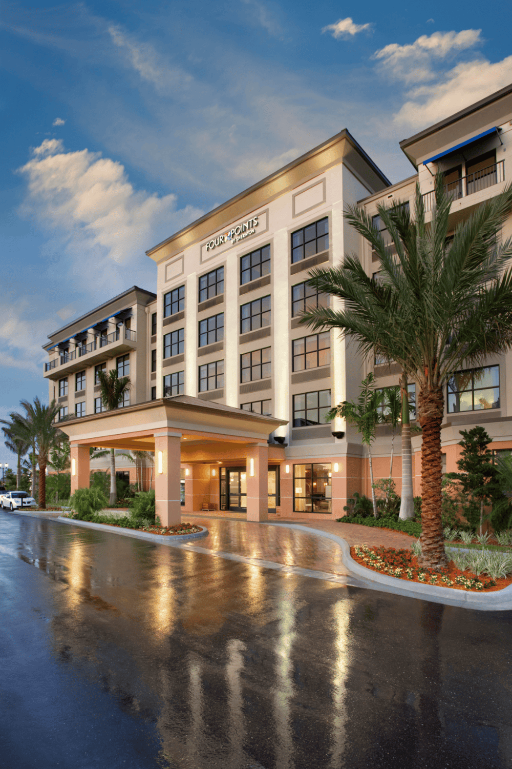 Contemporary hotel exterior at dusk, featuring palm trees and modern architecture in an inviting setting.