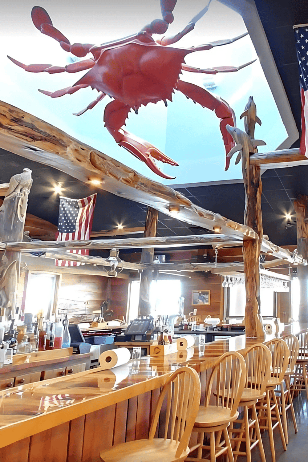 Crab sculpture hanging above a rustic bar in a seafood restaurant, American flags decoration, cozy atmosphere.