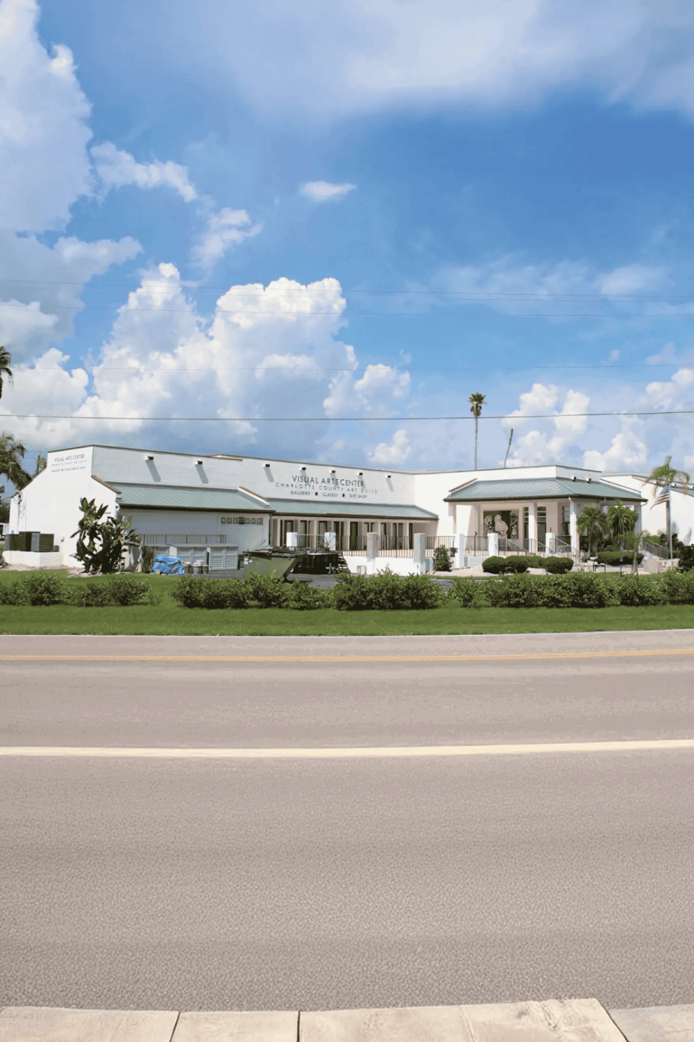 Quiet outdoor scene of a modern art center with blue sky and clouds in the background.