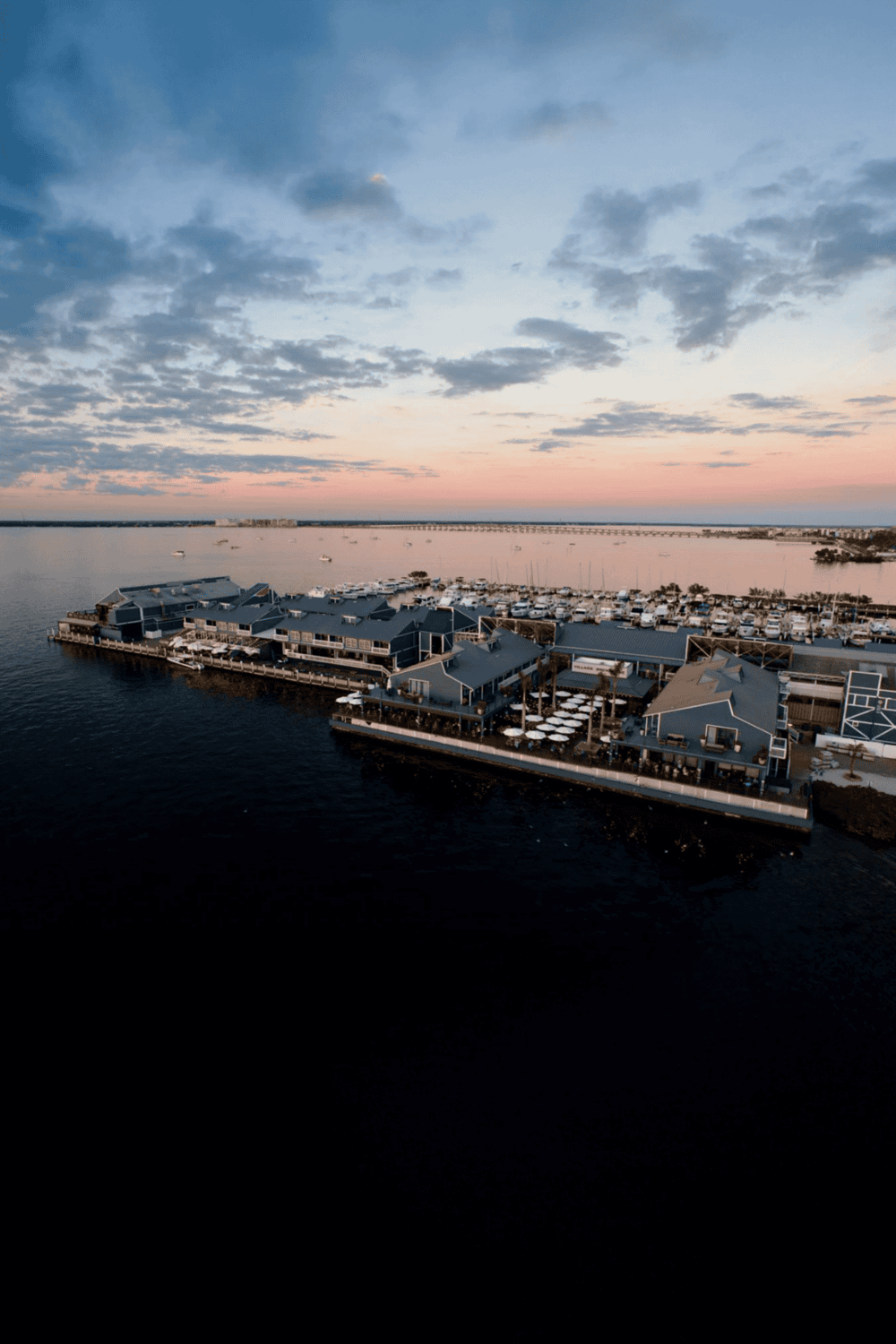 Waterfront resort with marina and modern buildings at sunset.