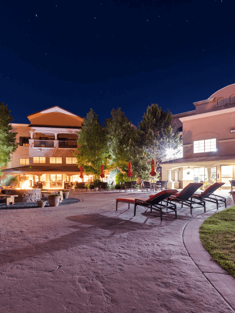 Outdoor hotel courtyard with lounge chairs and fire pit at night, perfect for relaxing and socializing.