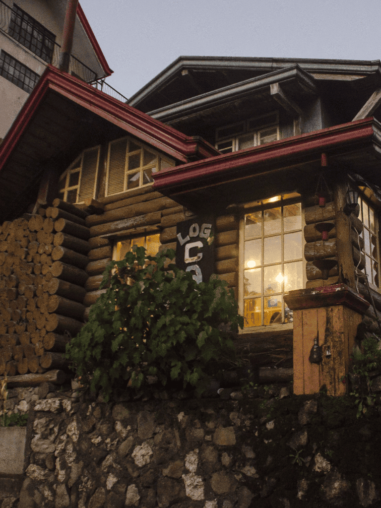 Cozy rustic log cabin with warm lighting and outdoor woodpile, perfect for nature lovers.