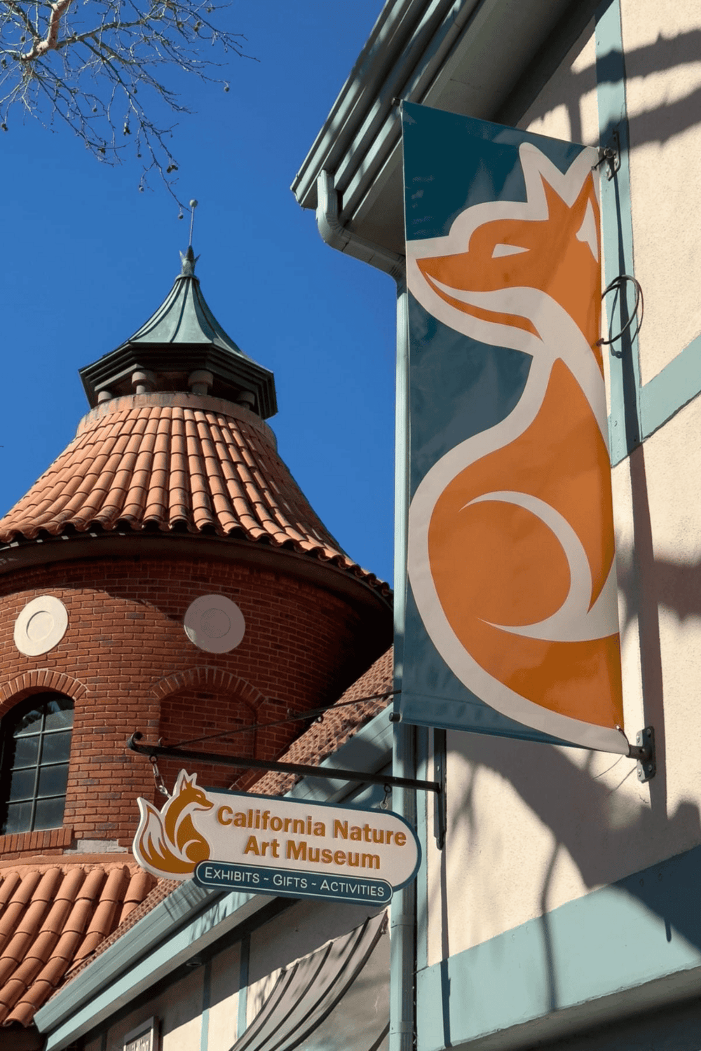 California Nature Art Museum sign with fox logo and blue sky background.