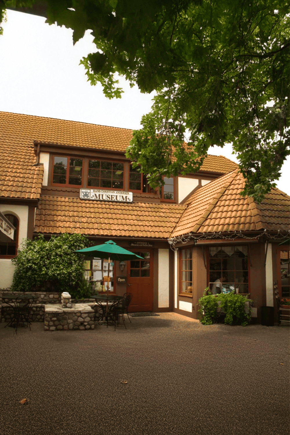Cozy museum building with outdoor dining area, lush greenery, and welcoming entrance, perfect for arts and culture explorations.