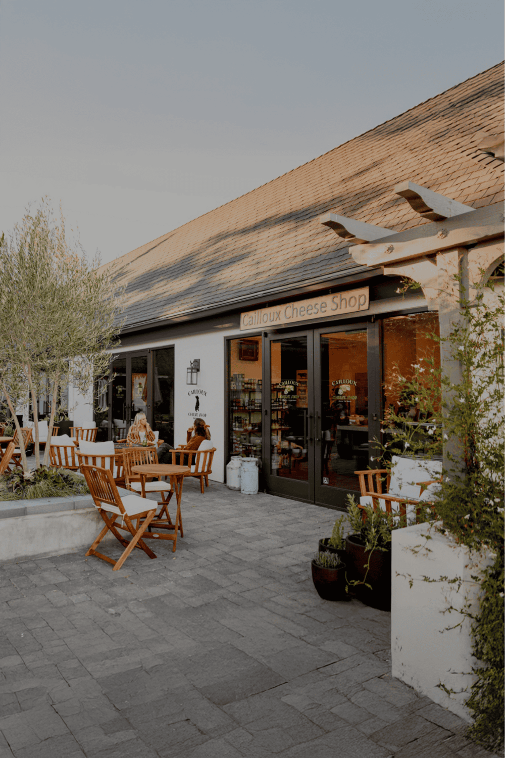 Cozy outdoor seating at Calloux Cheese Shop with rustic ambiance and fresh greenery.