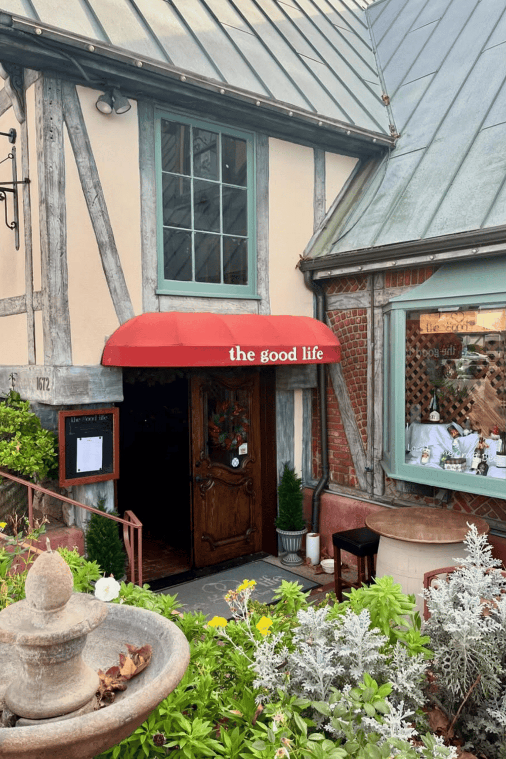 Cozy restaurant entrance with "the good life" red awning and charming outdoor decor, perfect for dining and relaxation.
