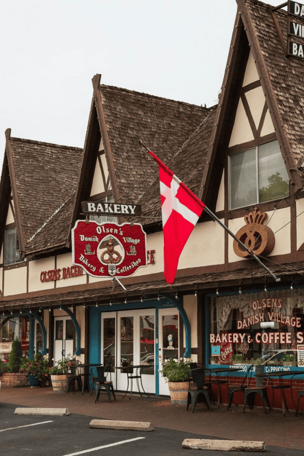 Charming Danish village bakery with a red and white flag, outdoor seating, and cozy vintage architecture for a delightful experience.