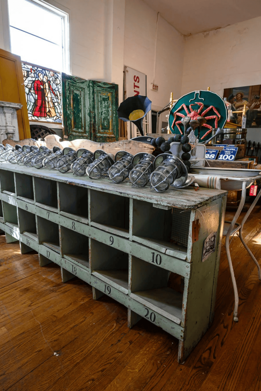 Vintage rustic glass lanterns on an antique wooden cubby shelf at an antique shop.