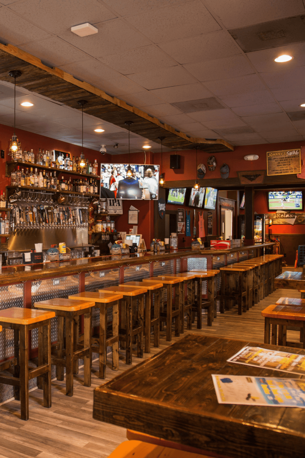 Cozy bar interior with wooden furnishings, multiple TV screens, and a fully stocked drink shelf, perfect for sports and social gatherings.