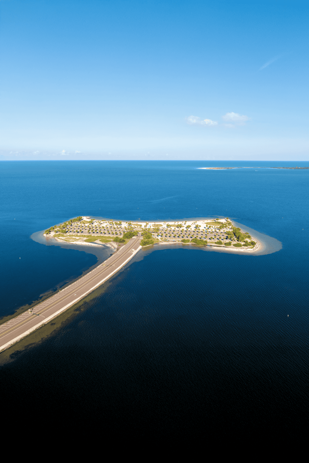 Aerial view of QuestForDirections island with parking, greenery, and surrounding ocean scenery.