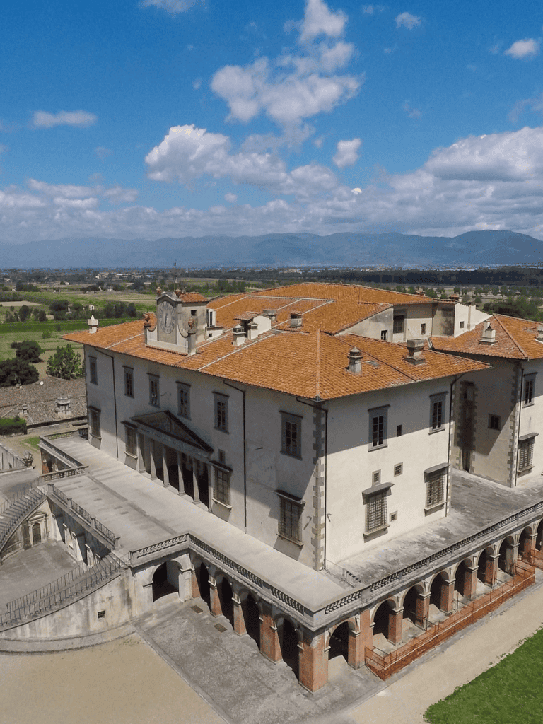 Historical Italian villa with scenic countryside backdrop, architecture, and terracotta roof tiles.