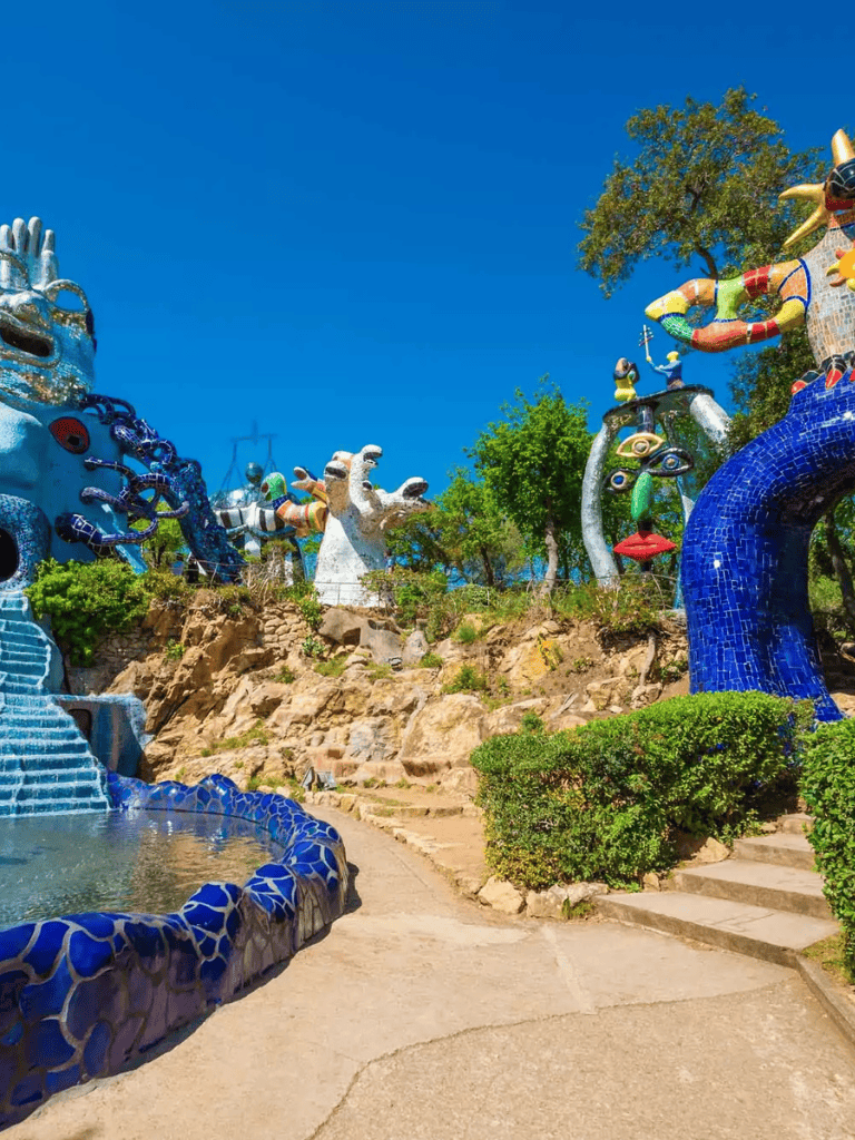 Colorful sculptures in a park with blue sky and greenery, showcasing unique outdoor art installations.