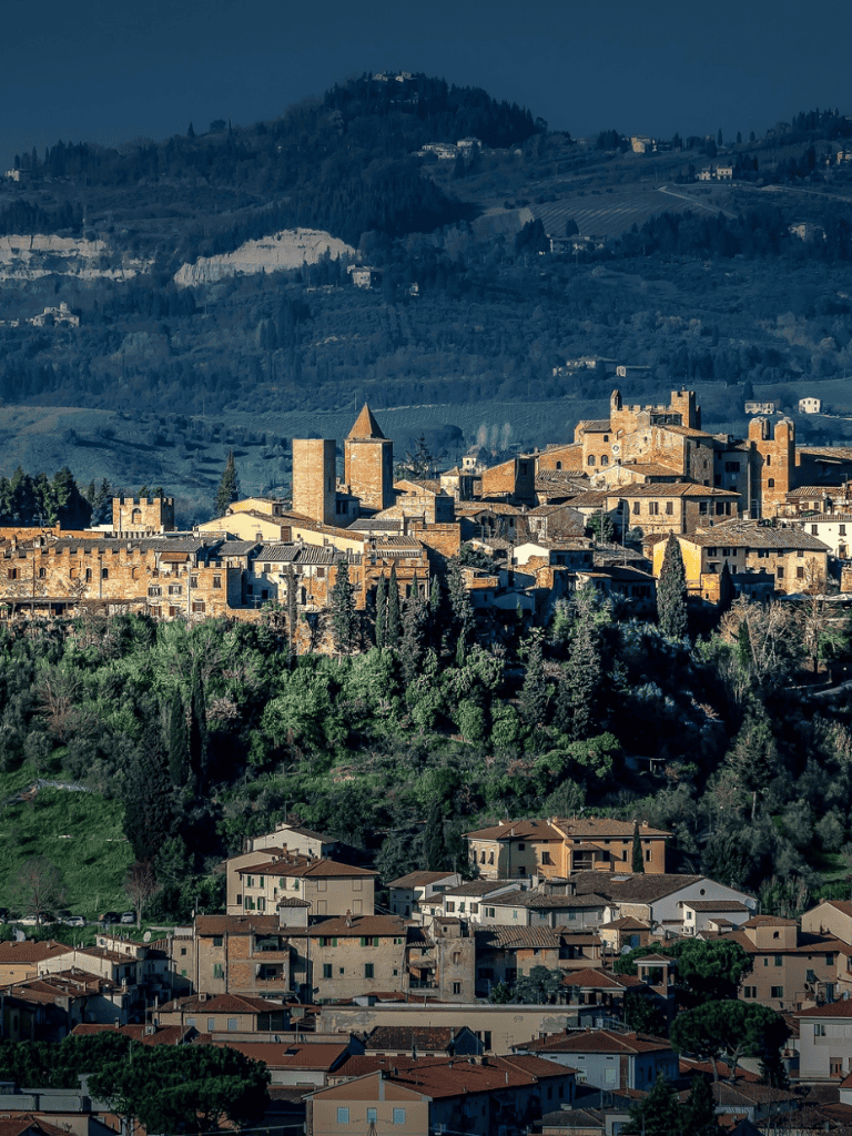 Medieval Italian hilltop town with historic stone buildings and lush green surrounding landscape.