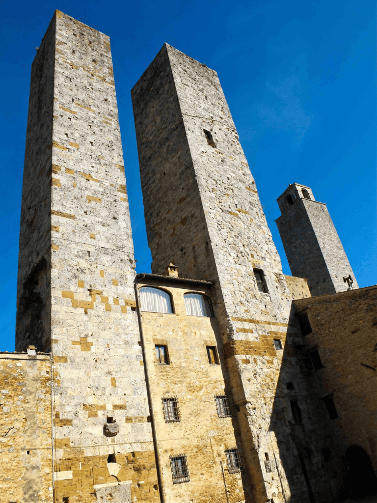 Ancient stone towers under a bright blue sky, showcasing historic architecture in a picturesque setting.