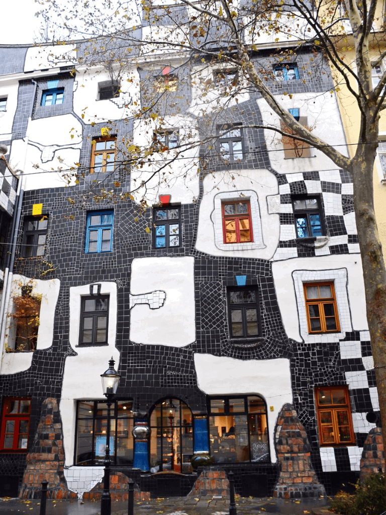Colorful modern building with unique mosaic facade and vibrant window frames, showcasing innovative architectural design.