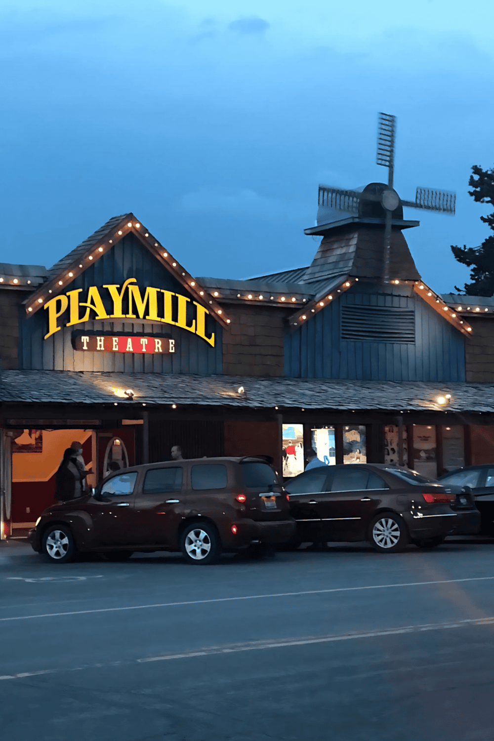 Charming Playmill Theatre building with vintage signage and exterior lighting at dusk.