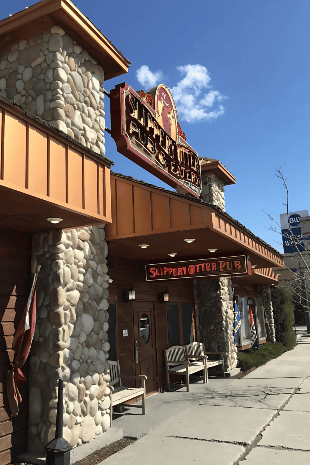 Cute pub with stone facade, welcoming outdoor seating, and signage for Slippery Otter Pub and Quest for Directions.