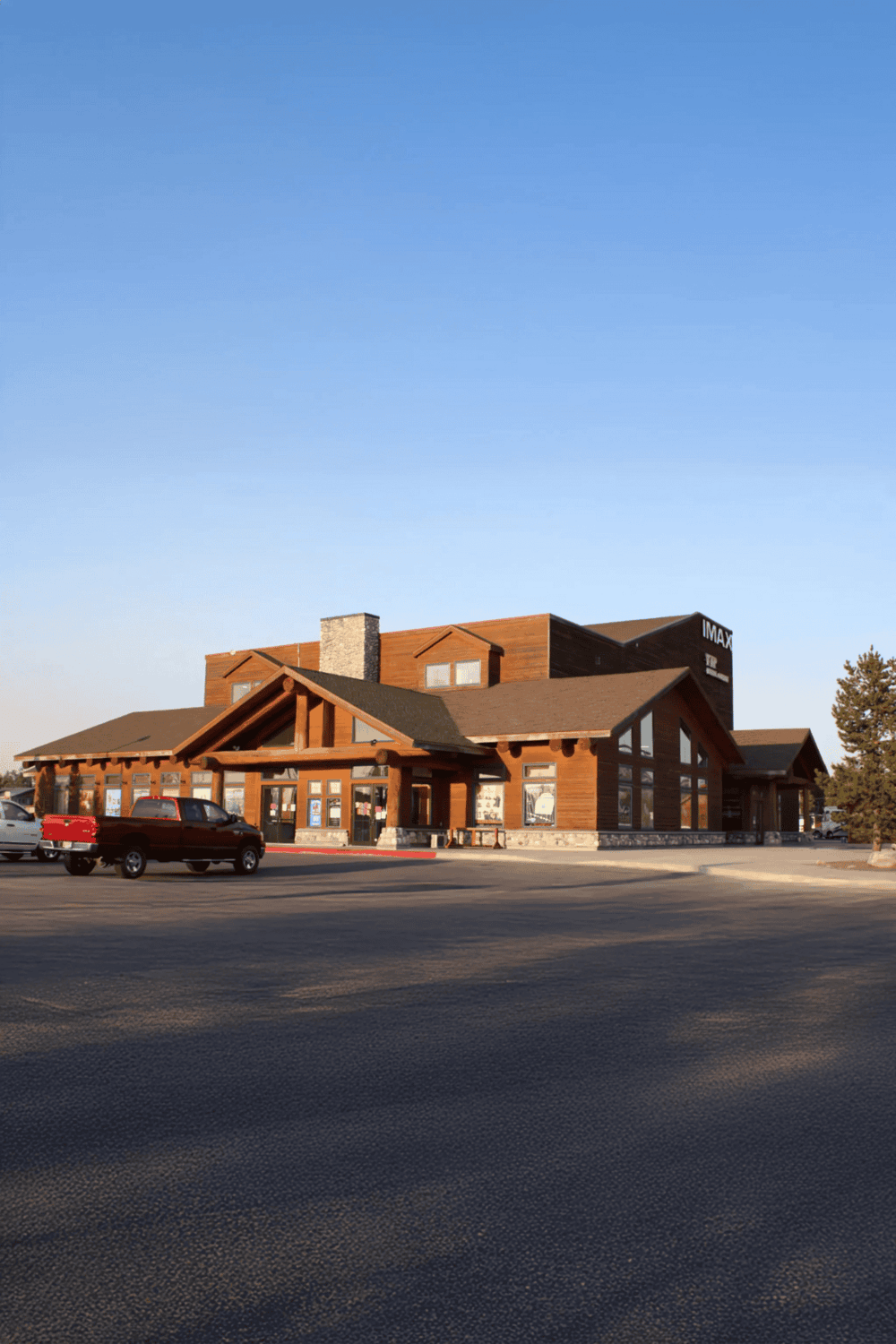 Modern commercial building with wood accents and large parking lot, designed for retail or entertainment purposes.