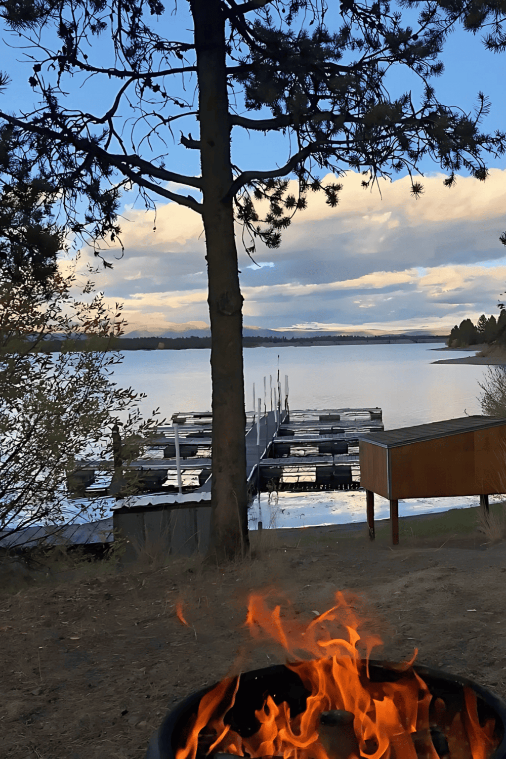 Cozy lakeside fire with dock and boat slips at sunset, scenic outdoor recreational area.