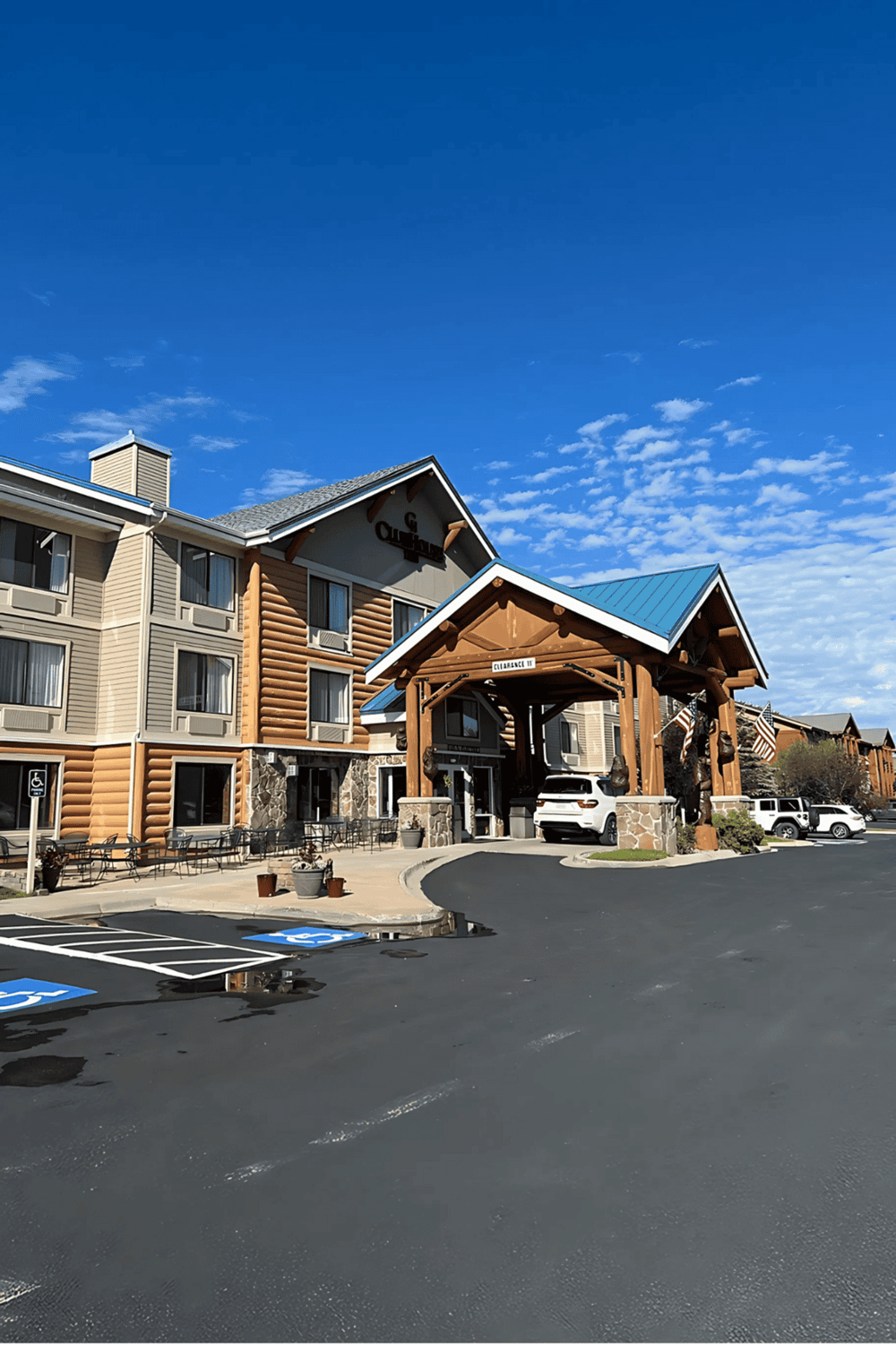 Modern hotel entrance with cabin-style architecture and accessible parking.