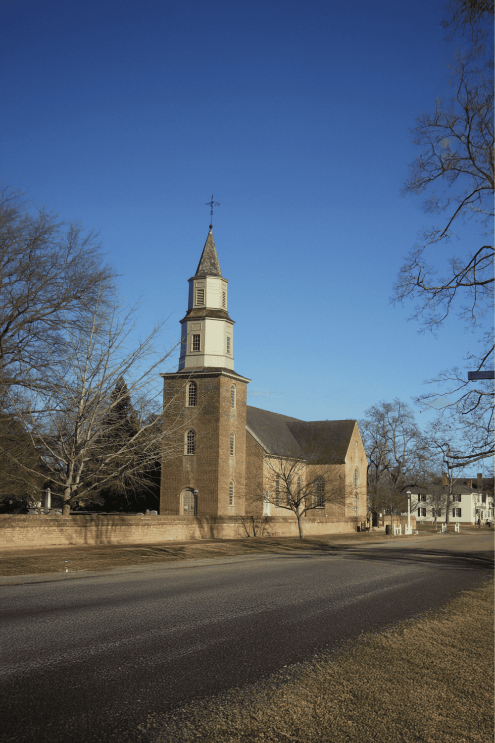 Quiet historic church with steeple, brick walls, and clear blue sky background.