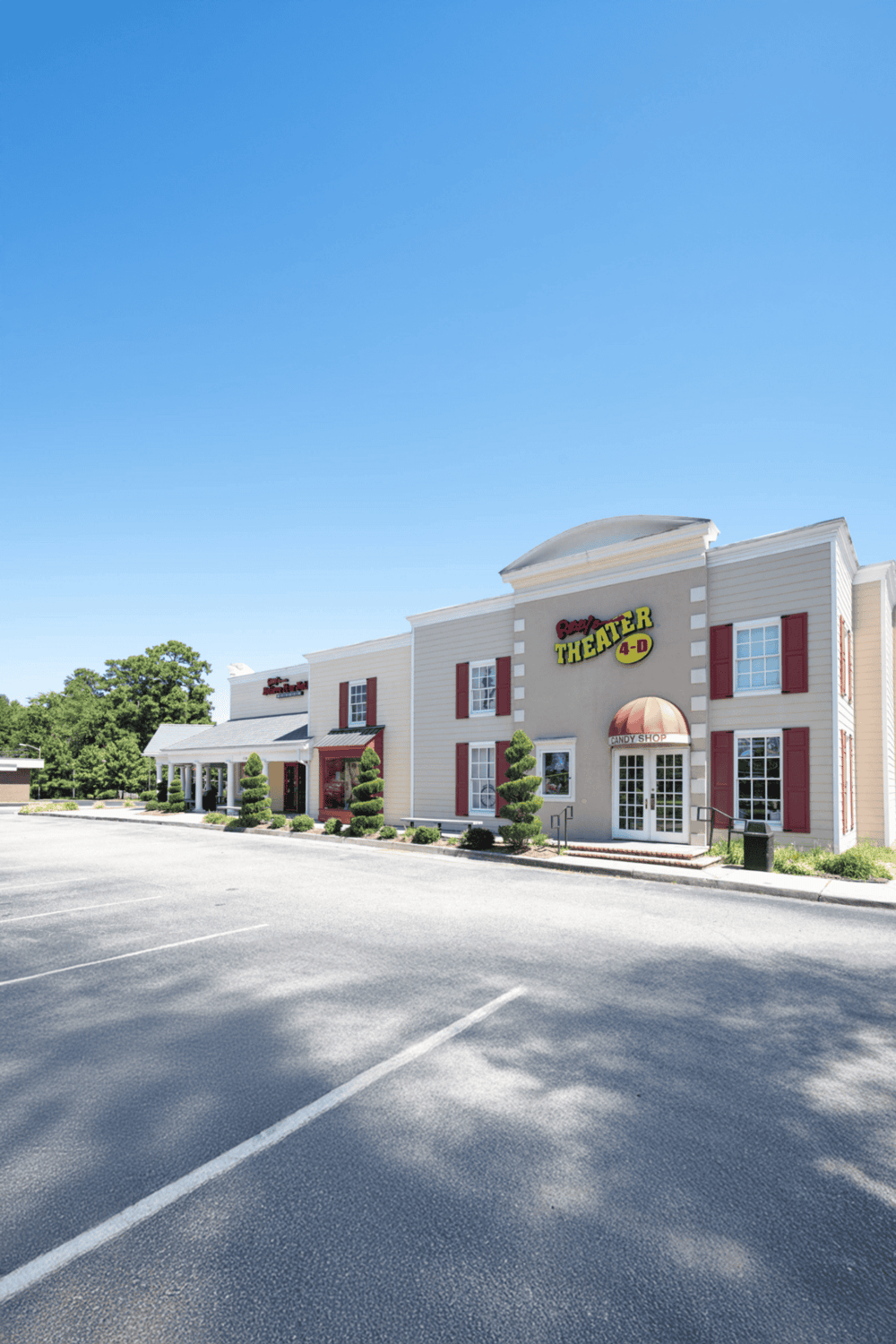 Bright shopping mall exterior with Quest for Directions signage, featuring a candy shop, under a clear blue sky.