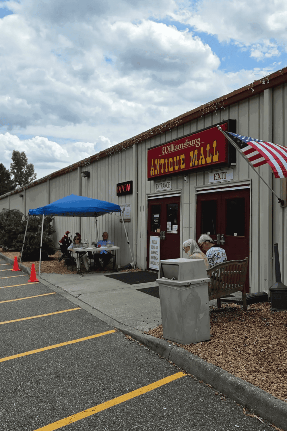 Antique mall storefront with outdoor seating and American flag, popular shopping destination, Williamsburg antique mall.