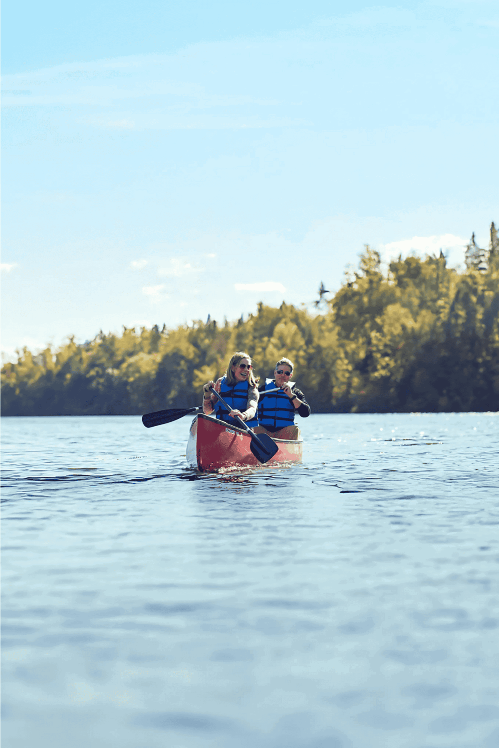 Paddle boat on calm lake with lush green trees in the background, sunny weather perfect for outdoor adventure.
