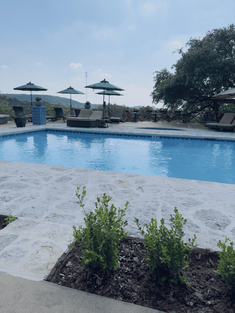 Relaxing outdoor pool area with seating and umbrellas, scenic view and lush greenery for a perfect getaway.